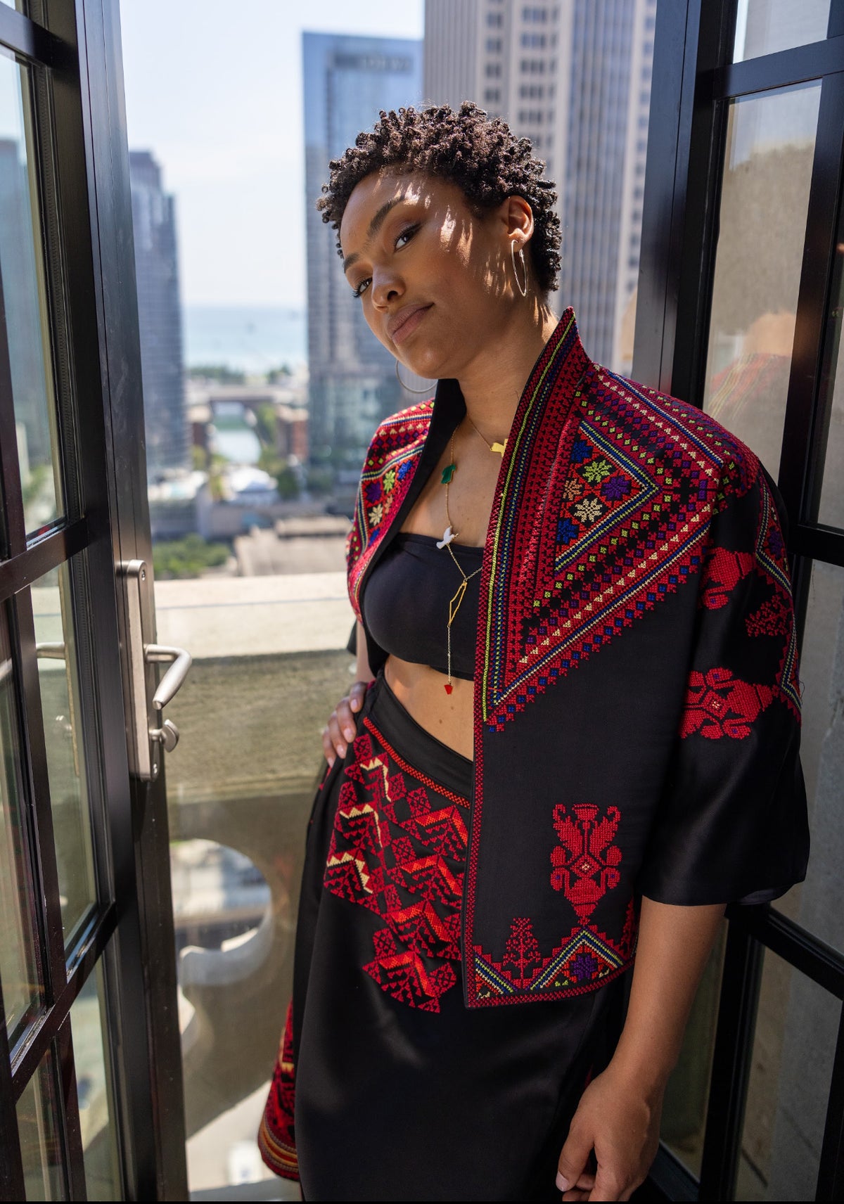Close-up of the Heritage Satin Skirt and embroidered jacket, showcasing the intricate red patterns and luxurious satin fabric.