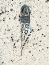 Close-up of a silver-plated pin in the shape of Palestine, showcasing delicate floral and geometric engravings on a stone background.